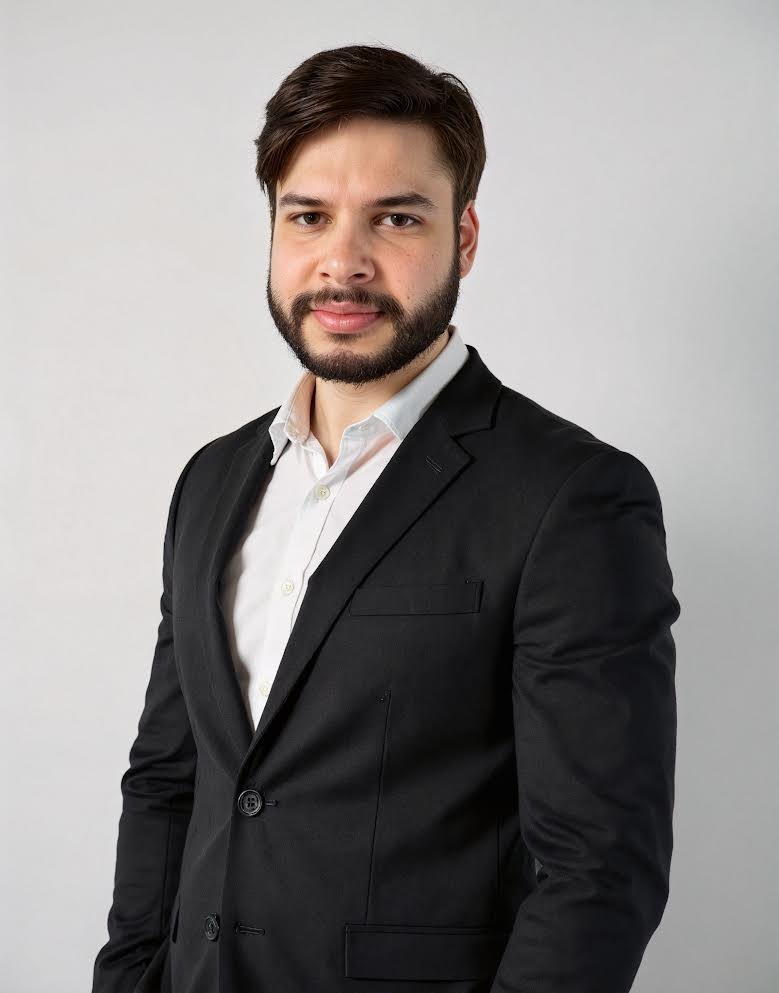 Portrait of Amrit, founder of RHAM, wearing a dark suit jacket and white shirt